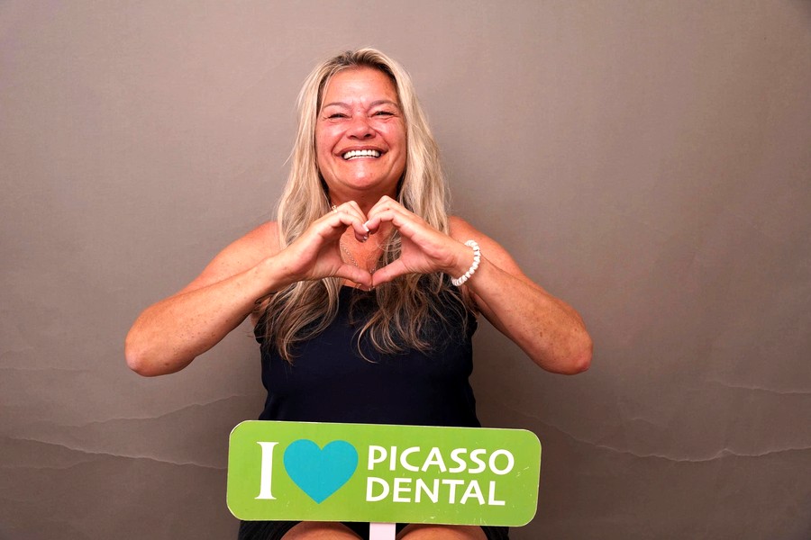 Joyful international patient making heart-hands gesture after dental treatment